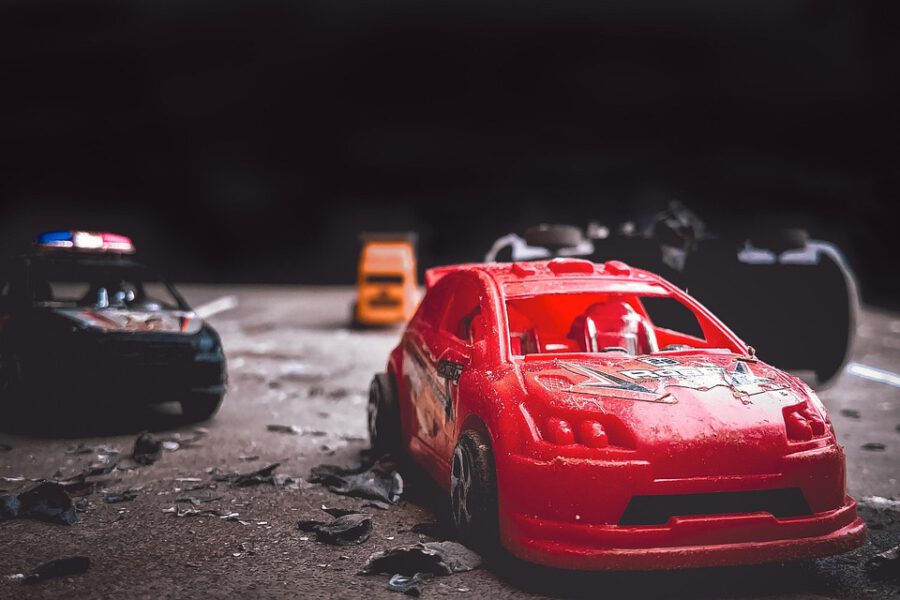 Symbolbil Unfall Spielzeugauto rot und Polizeitauto